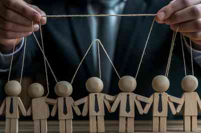 © Andres Mejia - stock.adobe.com Puppenspieler im Anzug mit Holzpuppen