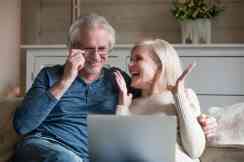 Zwei Pensionisten sitzen auf einer Couch mit einem Laptop