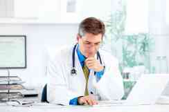Arzt sitzt vor Laptop